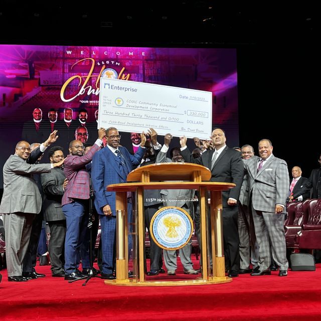 Group on a stage hold an oversized check