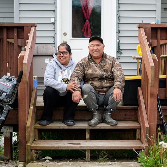 A man and woman sitting on the steps in front of their home