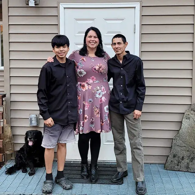 A mother with her two sons standing in front of their home