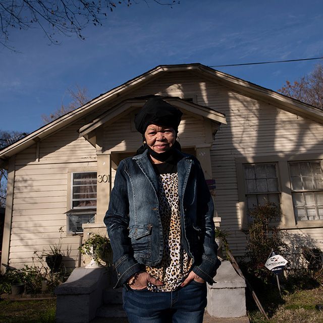 A woman standing in front of her home smiling