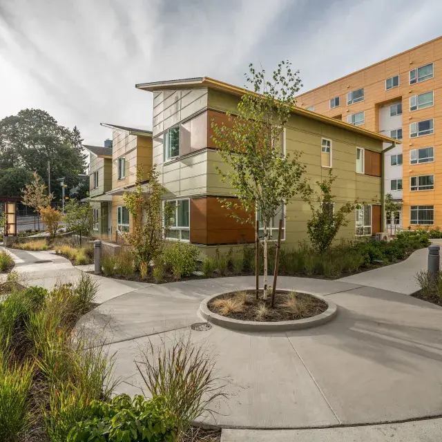 Midrise multifamily housing development with ample greenery and a circular walkway