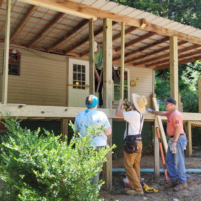 Three workers repairing a home damaged by a devastating flood in Eastern Kentucky