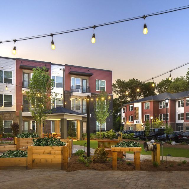 Courtyard of housing development at dusk with string lights and raised garden boxes