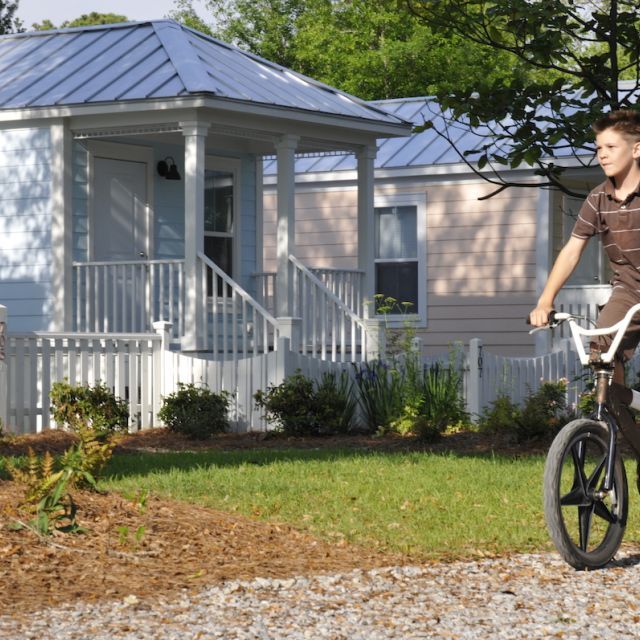 Young boy right biking pass colorful homes