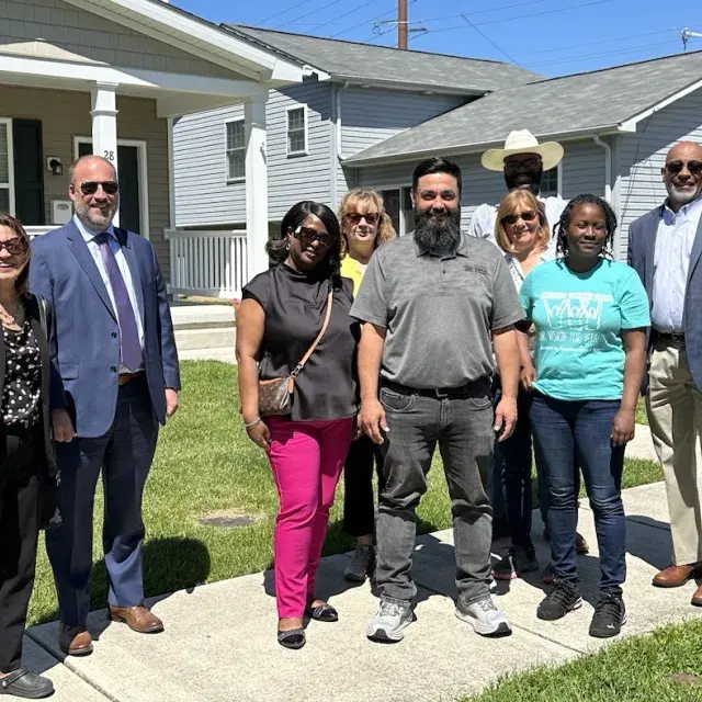 Group of smiling people standing in front of new homes