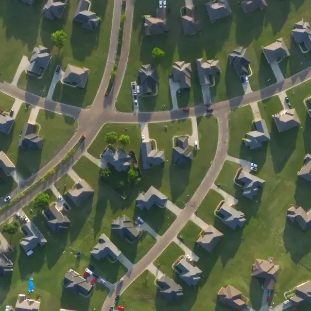 An aerial view of single-family homes and green lawns