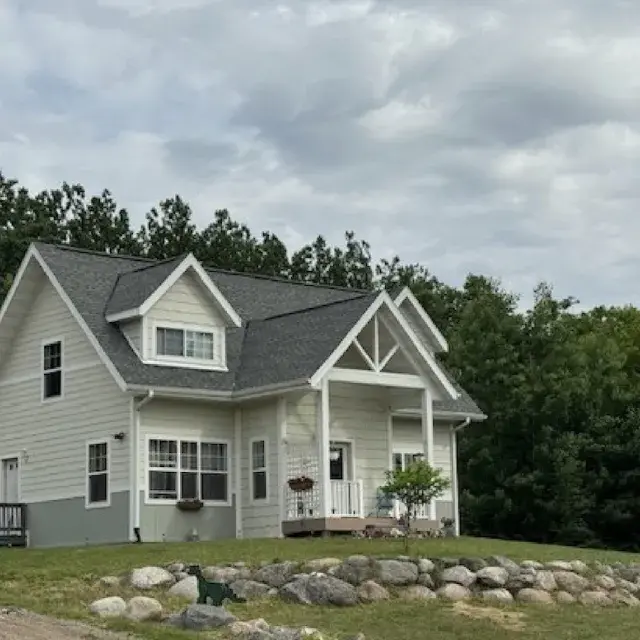 Yellow two-story house surrounded by a green yard and trees