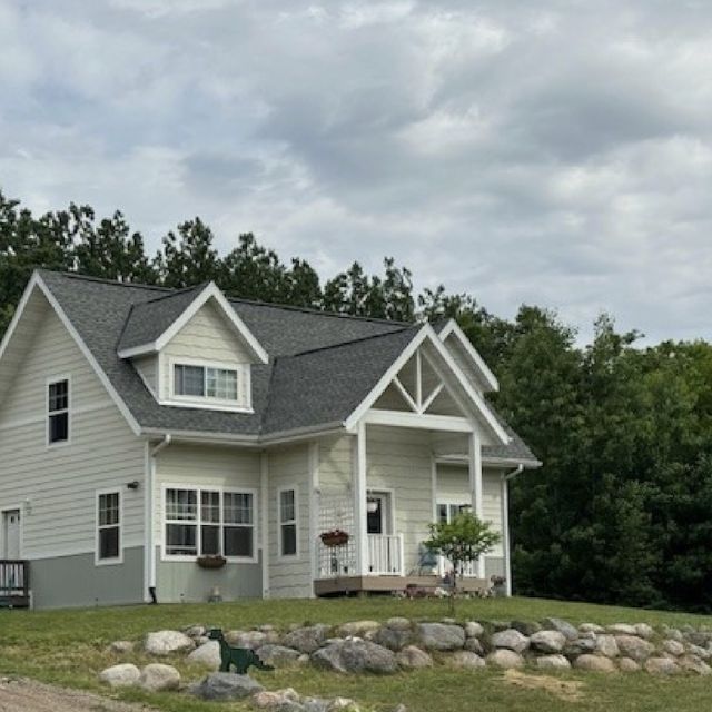 Yellow two-story house surrounded by a green yard and trees