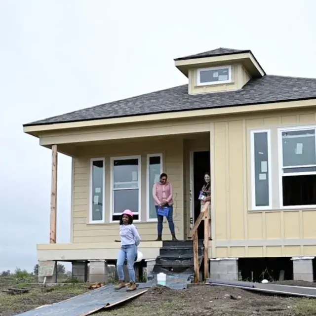 Construction workers walking out of yellow house being built