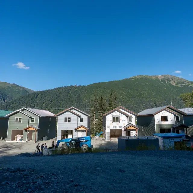 Row of six new singe-family homes with trees, mountains and blue sky in the background