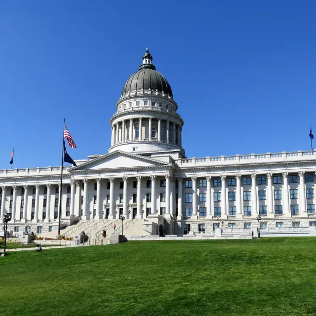 U.S. Capitol Building with green lawn in the foreground and blue sky in the background