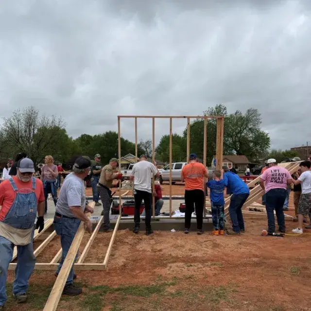 People in work clothing raising a wooden frame up together