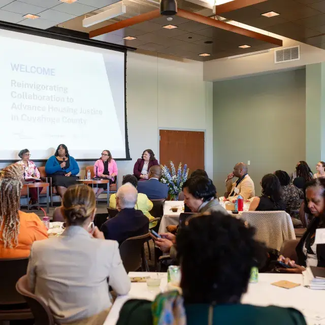 140 partners gather in a room and listen to a panel discussion. 