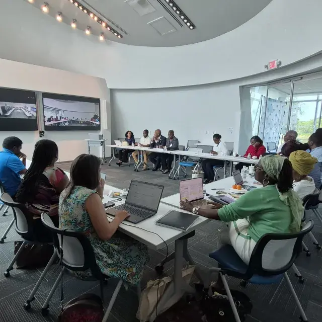 Attendees at the USVI Affordable Housing Workshop in a conference room with two screen projections