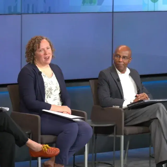 Four people sit on chairs on stage in conversation