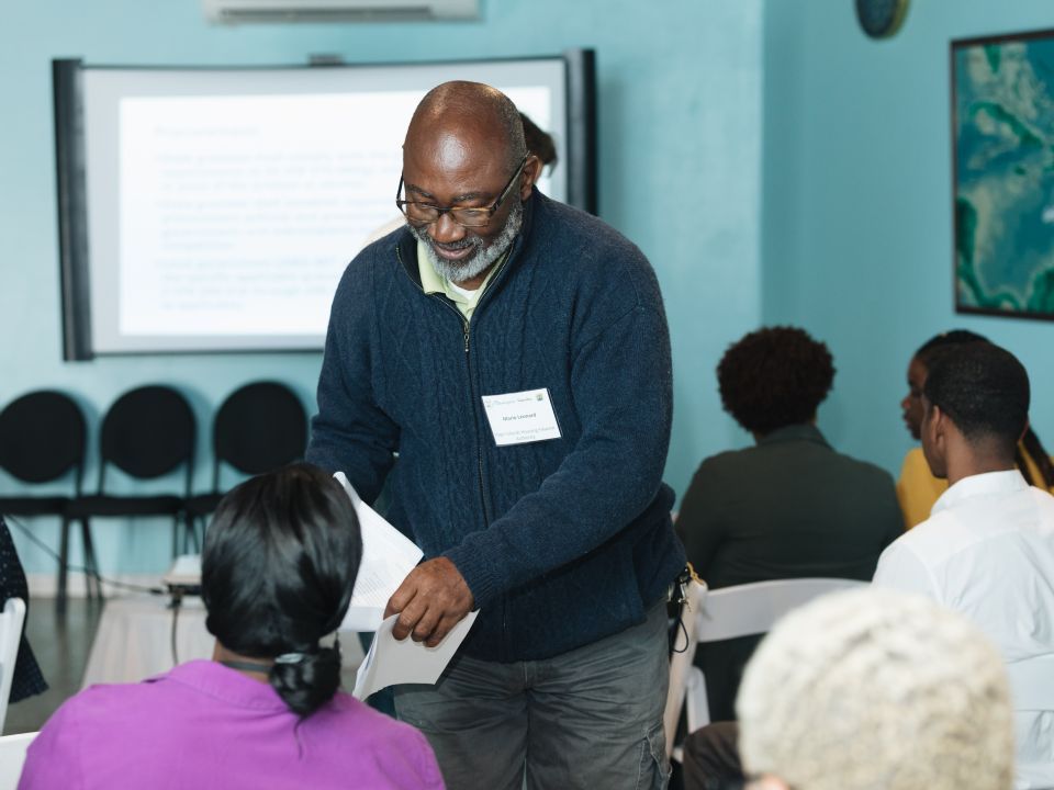 A man handing out papers to a room of students