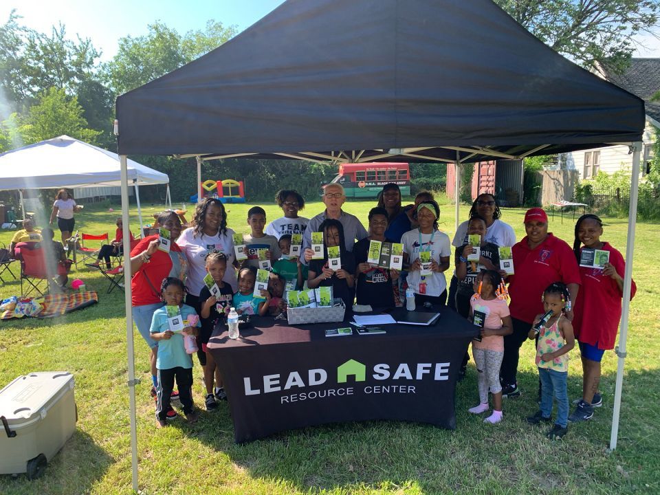 A group of people under a tent displaying information for Lead Safe Resource Center