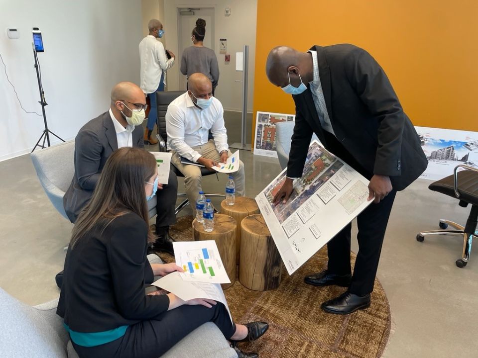 A team of people look at a presentation board, while the man holding it points