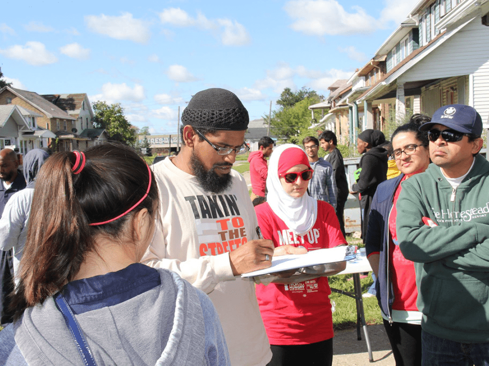 A man writing and handing out assignments to a group of volunteers