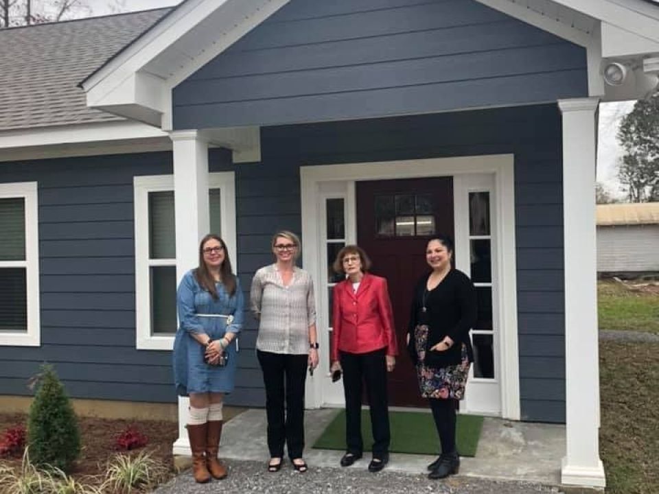 Four people standing outside of a house