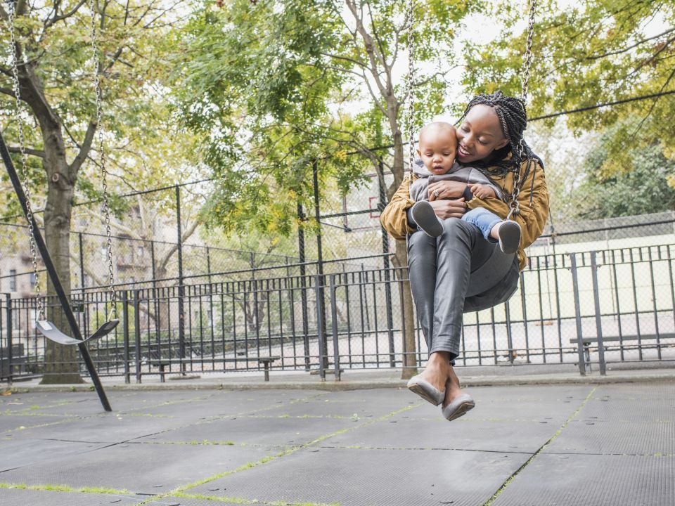 A mother swinging with her child in a park