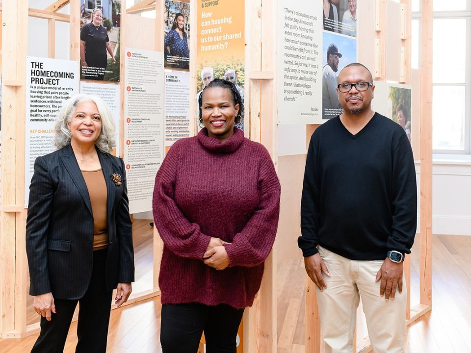 Two woman and a man standing in front of a wooden exhibit