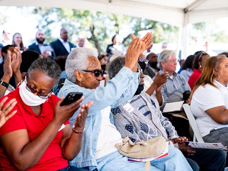 An audience of people sitting outside and clapping