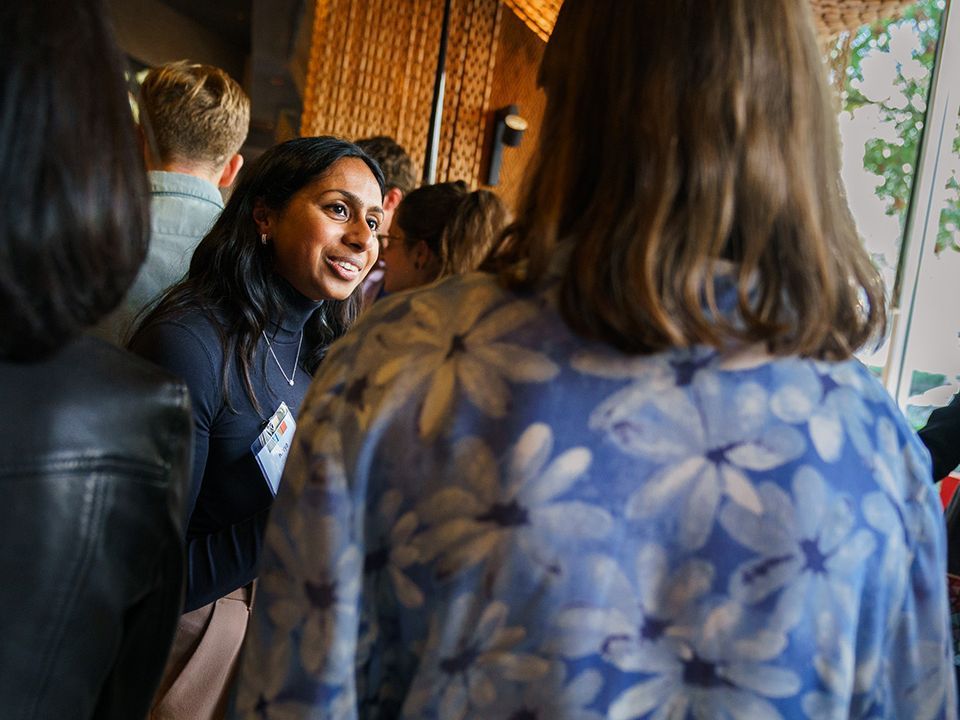 A person smiling and standing in a group of people