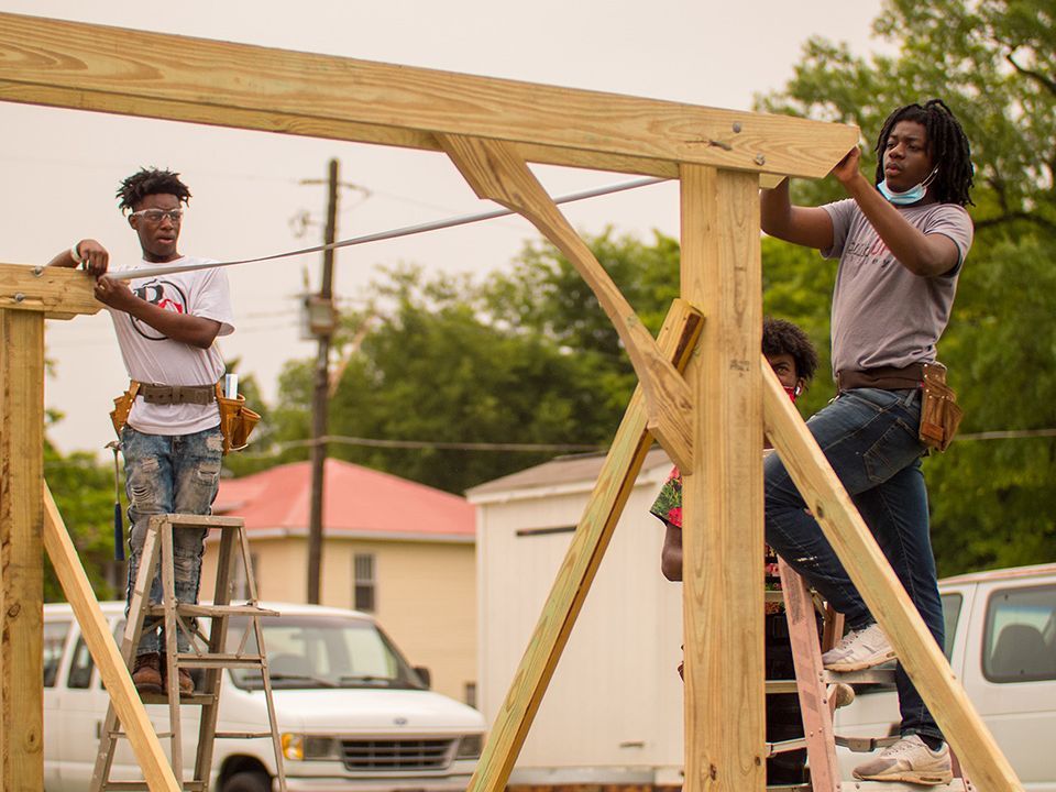 Two young men building a wooden structure
