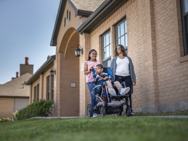 A mother walking with her daughter and pushing her son in a stroller 